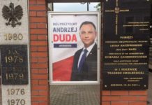 Brzesko. Plakat wyborczy na pomniku, obok tablicy upamiętniającej katastrofę smoleńską