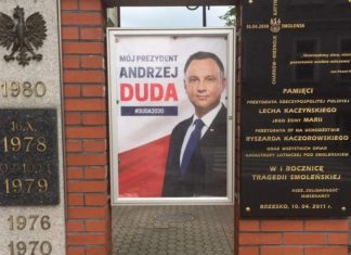 Brzesko. Plakat wyborczy na pomniku, obok tablicy upamiętniającej katastrofę smoleńską
