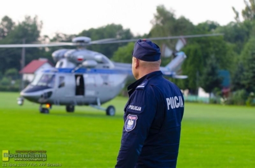 policjant na tle policyjnego helikoptera biorącego udział w poszukiwaniach