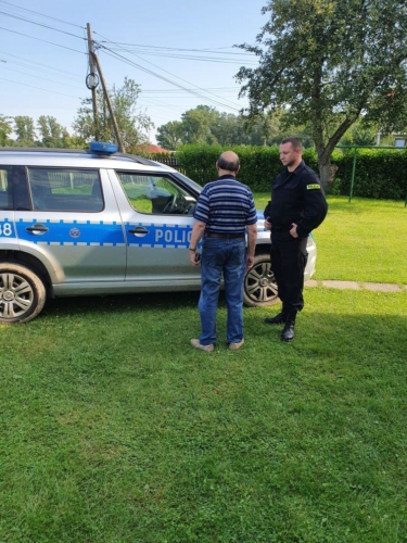 policjant rozmawiający z odnalezionym mężczyzną przy radiowozie policyjnym (2)